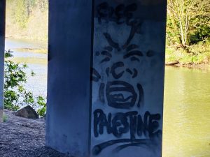 Graffiti on an electrical box, illustrated with a grimacing face and reading 'Free Palestine'